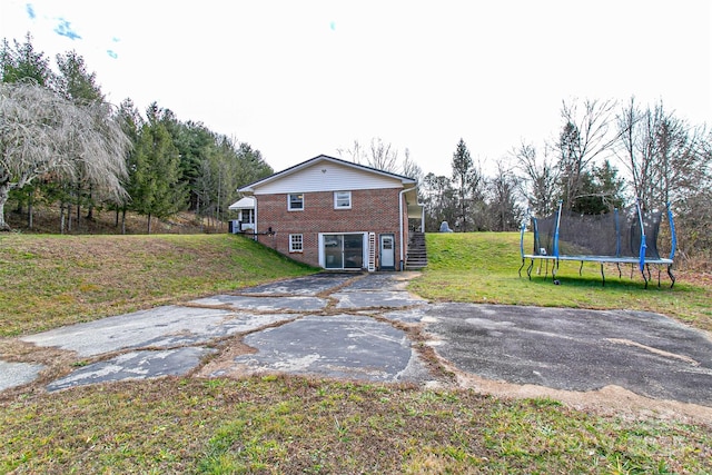 rear view of house with a trampoline and a yard