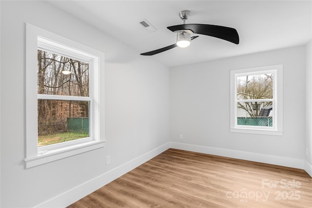 empty room with ceiling fan, hardwood / wood-style floors, and a healthy amount of sunlight