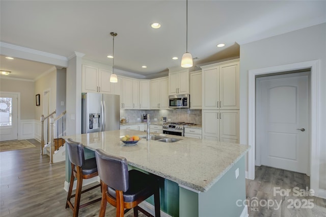 kitchen with light stone counters, sink, stainless steel appliances, and decorative light fixtures