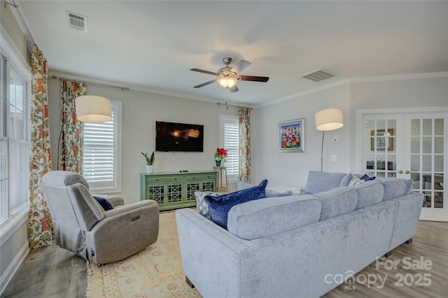 living room with french doors, crown molding, hardwood / wood-style flooring, ceiling fan, and a healthy amount of sunlight