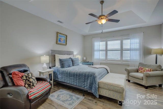 bedroom featuring hardwood / wood-style flooring, ceiling fan, and a tray ceiling