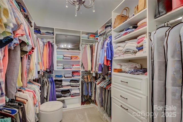 walk in closet with light carpet and a notable chandelier