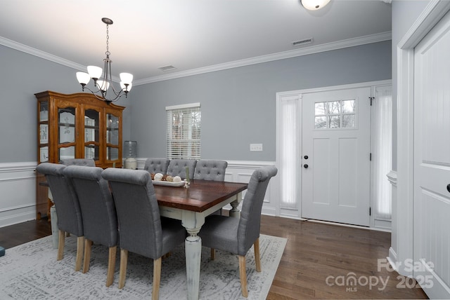 dining room featuring crown molding, dark wood-type flooring, and a chandelier