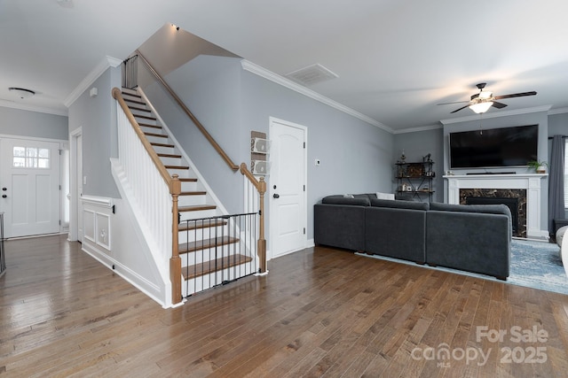 living room with wood-type flooring, ceiling fan, crown molding, and a premium fireplace