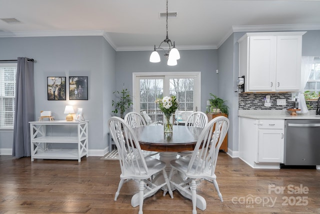 dining room with dark hardwood / wood-style flooring, crown molding, a wealth of natural light, and a notable chandelier