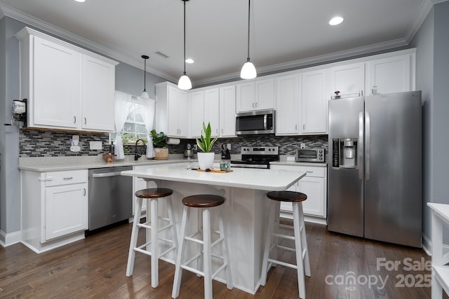 kitchen featuring pendant lighting, a center island, white cabinets, dark hardwood / wood-style flooring, and stainless steel appliances