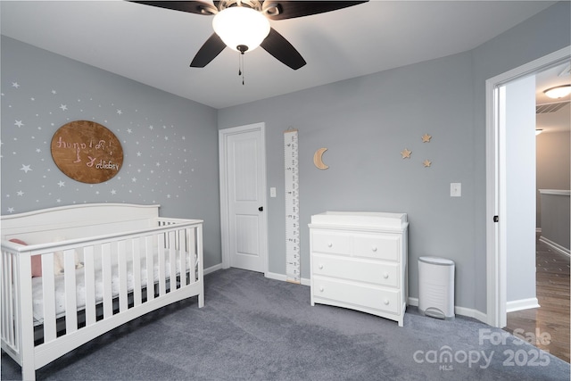 bedroom with ceiling fan, a crib, and dark colored carpet