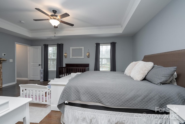 bedroom featuring dark hardwood / wood-style flooring, a tray ceiling, and ceiling fan