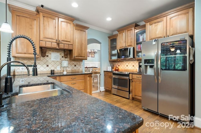 kitchen with sink, stainless steel appliances, backsplash, crown molding, and pendant lighting