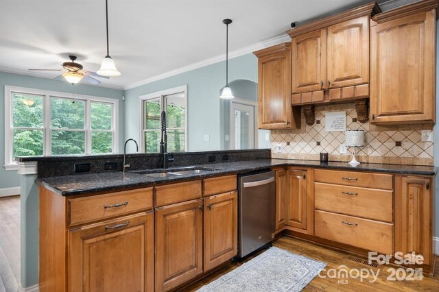 kitchen featuring pendant lighting, dishwasher, dark stone countertops, tasteful backsplash, and light hardwood / wood-style floors