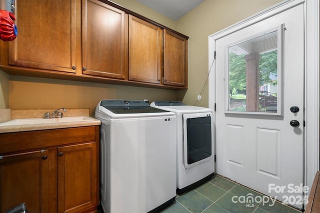 laundry area featuring cabinets, separate washer and dryer, dark tile patterned floors, and sink