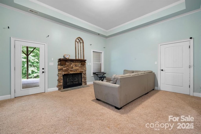 carpeted living room with a raised ceiling, a stone fireplace, and crown molding