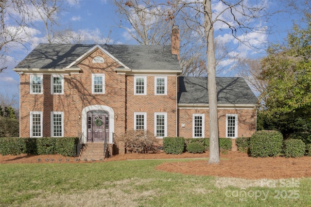 colonial-style house featuring a front lawn