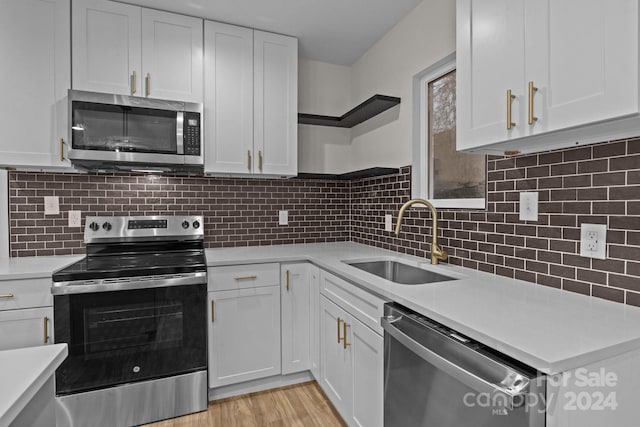 kitchen featuring decorative backsplash, white cabinetry, sink, and appliances with stainless steel finishes