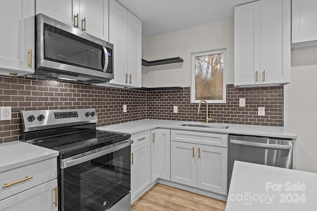 kitchen with white cabinets, appliances with stainless steel finishes, backsplash, and sink