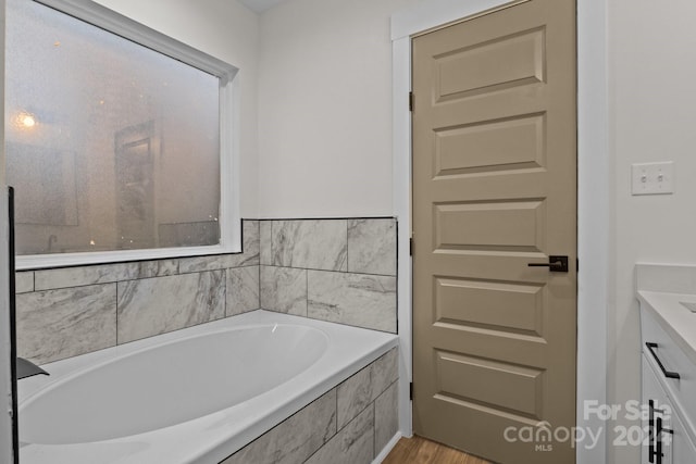 bathroom with vanity and a relaxing tiled tub