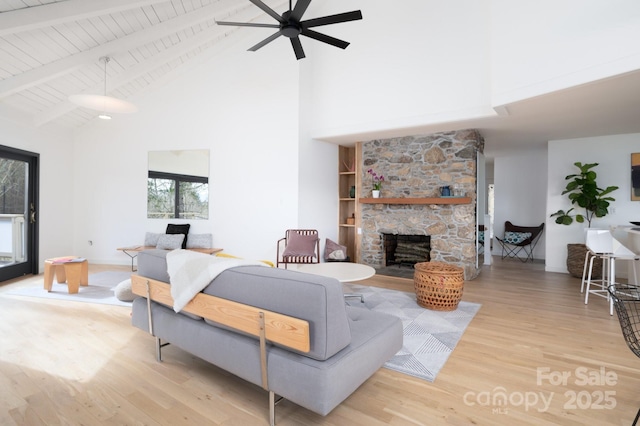 living area with beamed ceiling, wood finished floors, wooden ceiling, a fireplace, and ceiling fan