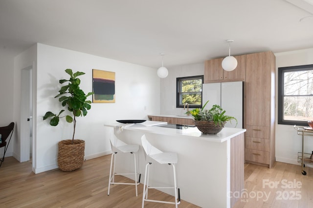 kitchen with a wealth of natural light, light wood-style flooring, freestanding refrigerator, and a kitchen island