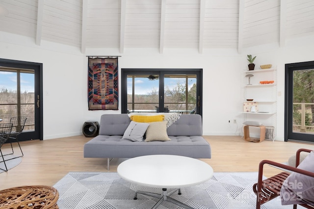 living room with french doors, beam ceiling, baseboards, and wood finished floors