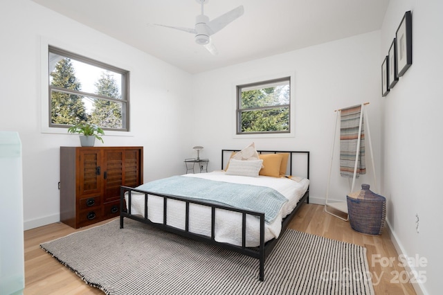 bedroom with baseboards, light wood finished floors, and ceiling fan