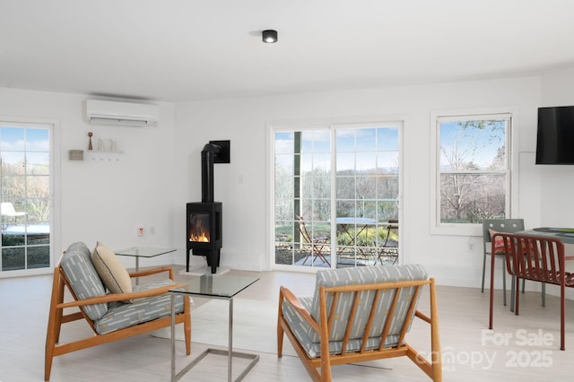 living area featuring a wood stove, light wood-type flooring, a wealth of natural light, and a wall mounted AC