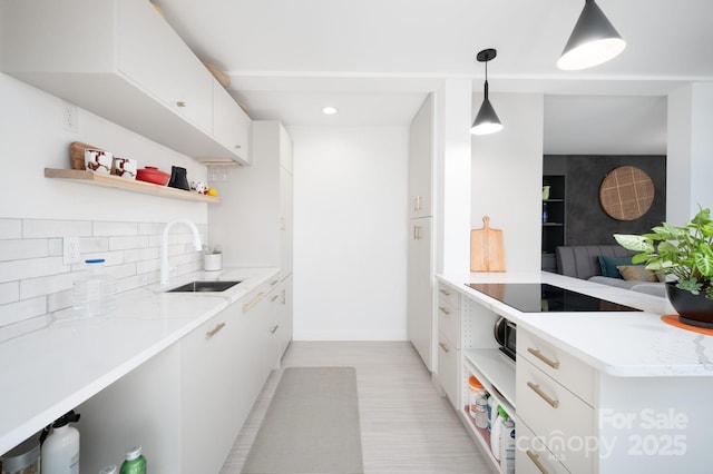 kitchen with backsplash, open shelves, white cabinets, black electric cooktop, and a sink