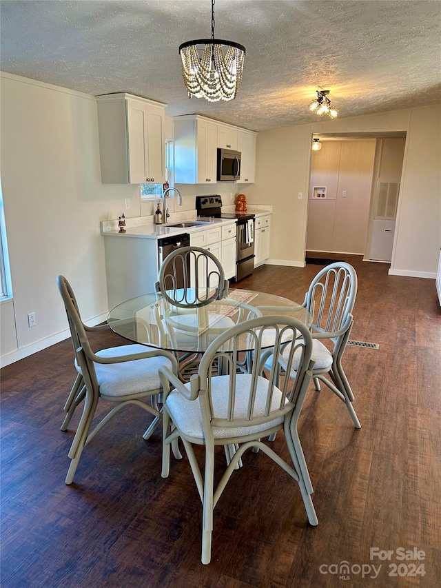 dining room featuring a textured ceiling, dark hardwood / wood-style floors, an inviting chandelier, and sink