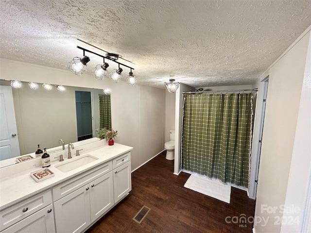 bathroom featuring vanity, wood-type flooring, a textured ceiling, and toilet