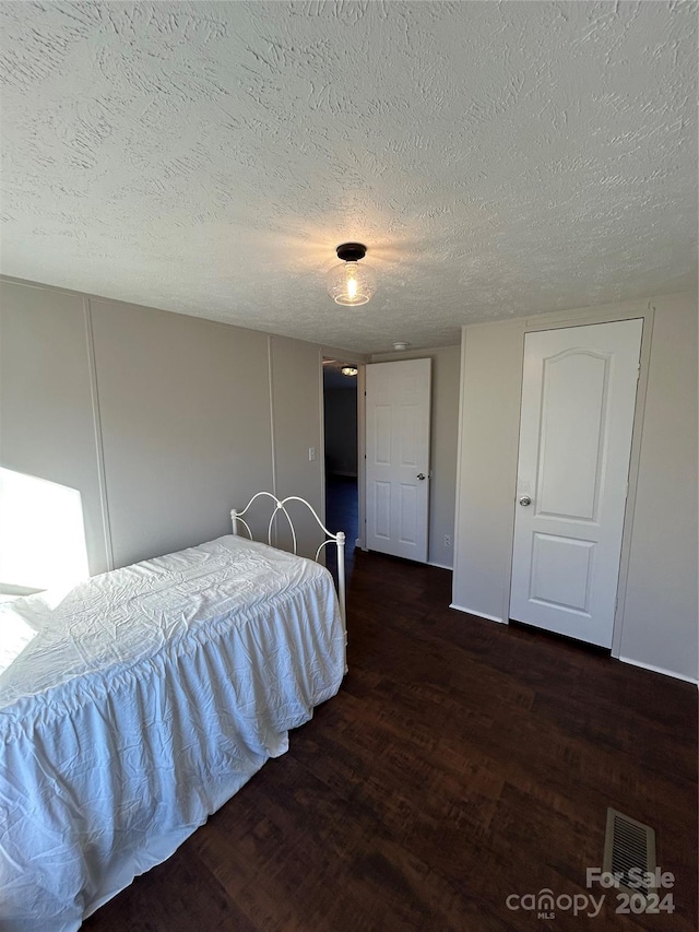 bedroom featuring dark hardwood / wood-style flooring and a textured ceiling