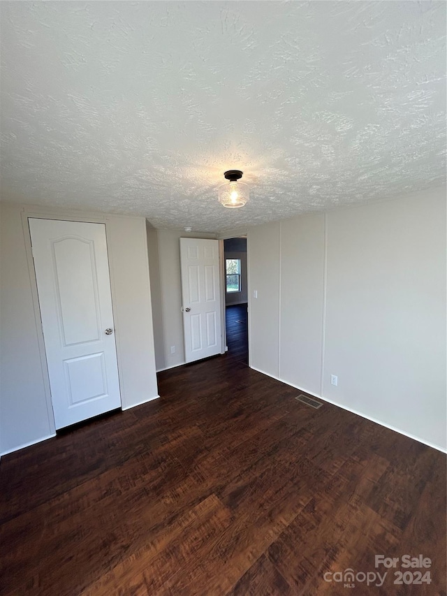 unfurnished room with dark hardwood / wood-style flooring and a textured ceiling