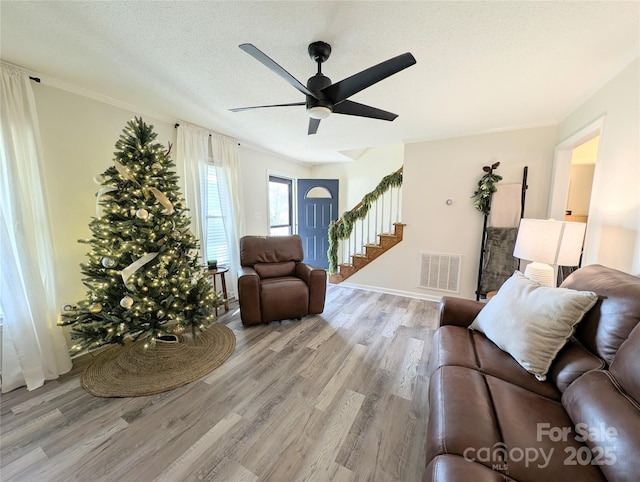 living room with a textured ceiling, light hardwood / wood-style floors, and ceiling fan