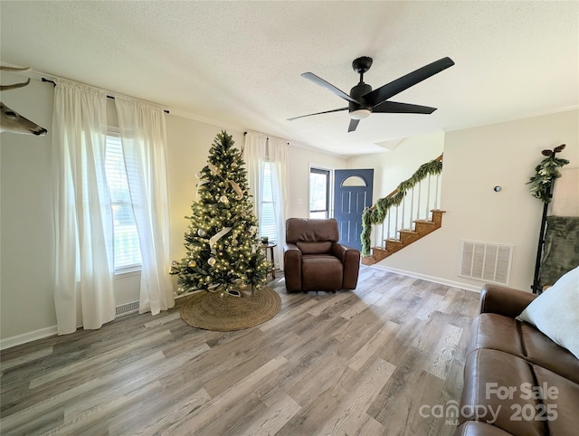 living room with a wealth of natural light, ceiling fan, light hardwood / wood-style floors, and a textured ceiling