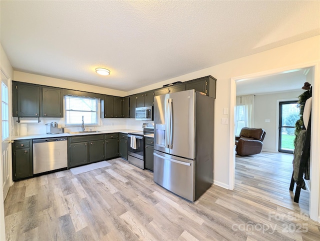 kitchen featuring a textured ceiling, light hardwood / wood-style floors, sink, and stainless steel appliances