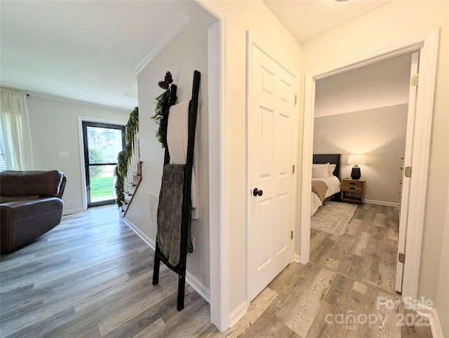 corridor with crown molding and light hardwood / wood-style flooring