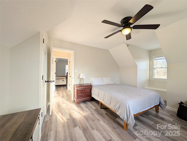 bedroom featuring ceiling fan, lofted ceiling, and light hardwood / wood-style flooring