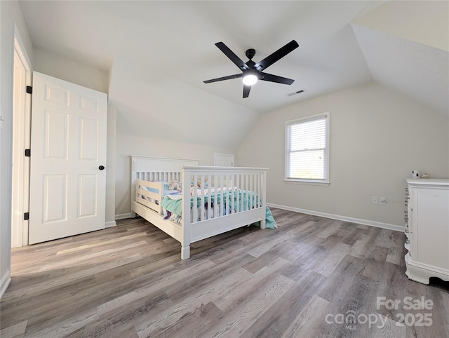 unfurnished bedroom with ceiling fan, light hardwood / wood-style flooring, a nursery area, and vaulted ceiling