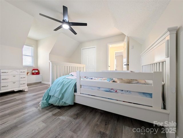 bedroom with ceiling fan, wood-type flooring, a textured ceiling, lofted ceiling, and a closet