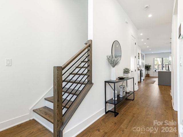 staircase with hardwood / wood-style flooring and sink