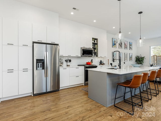 kitchen with a kitchen island with sink, sink, white cabinets, and appliances with stainless steel finishes