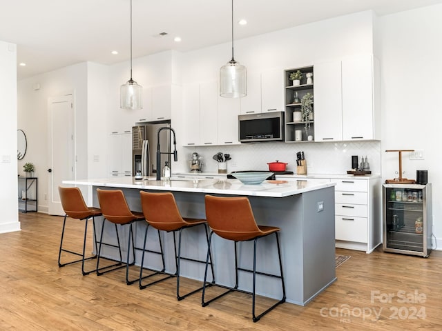 kitchen with decorative light fixtures, stainless steel appliances, and a center island with sink