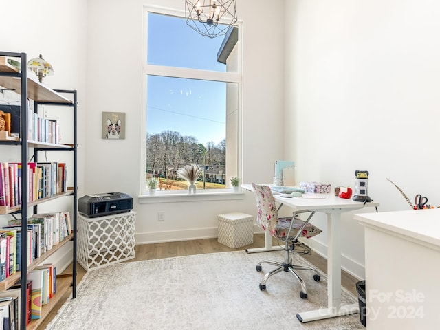 office with hardwood / wood-style floors and a notable chandelier