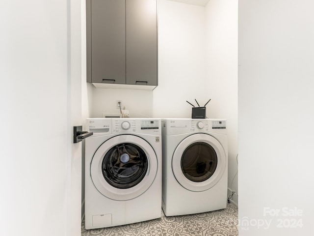 laundry area featuring washer and dryer, light tile patterned flooring, and cabinets