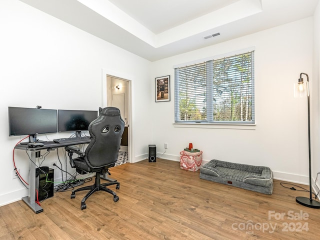 office area with hardwood / wood-style floors and a raised ceiling