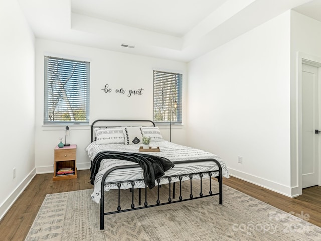 bedroom with a tray ceiling and hardwood / wood-style floors