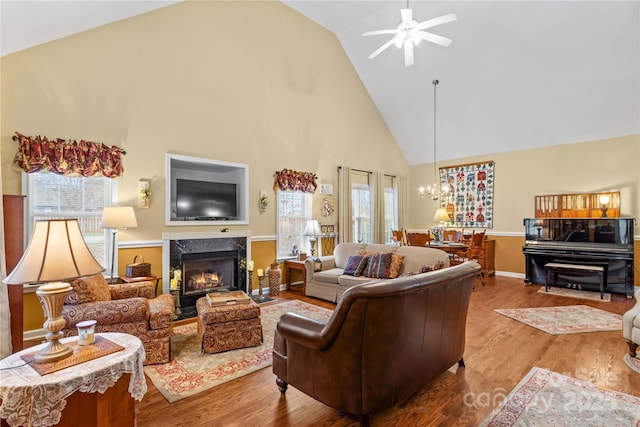 living room with ceiling fan with notable chandelier, hardwood / wood-style flooring, a wealth of natural light, and a premium fireplace