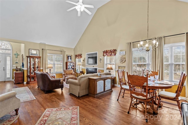 living room featuring ceiling fan with notable chandelier, wood-type flooring, and high vaulted ceiling