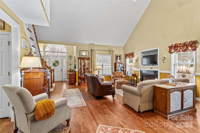 living room featuring a high end fireplace, high vaulted ceiling, and hardwood / wood-style flooring