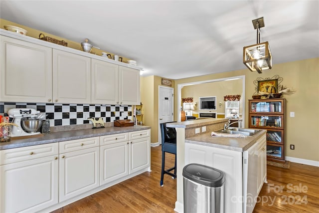 kitchen featuring white cabinets, backsplash, sink, and an island with sink