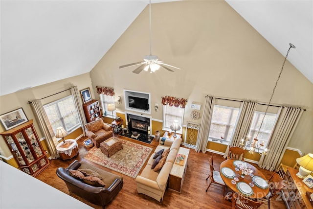 living room featuring hardwood / wood-style floors, ceiling fan, a fireplace, and high vaulted ceiling