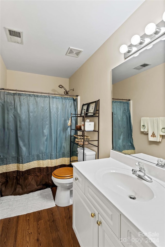 bathroom featuring hardwood / wood-style flooring, vanity, toilet, and walk in shower